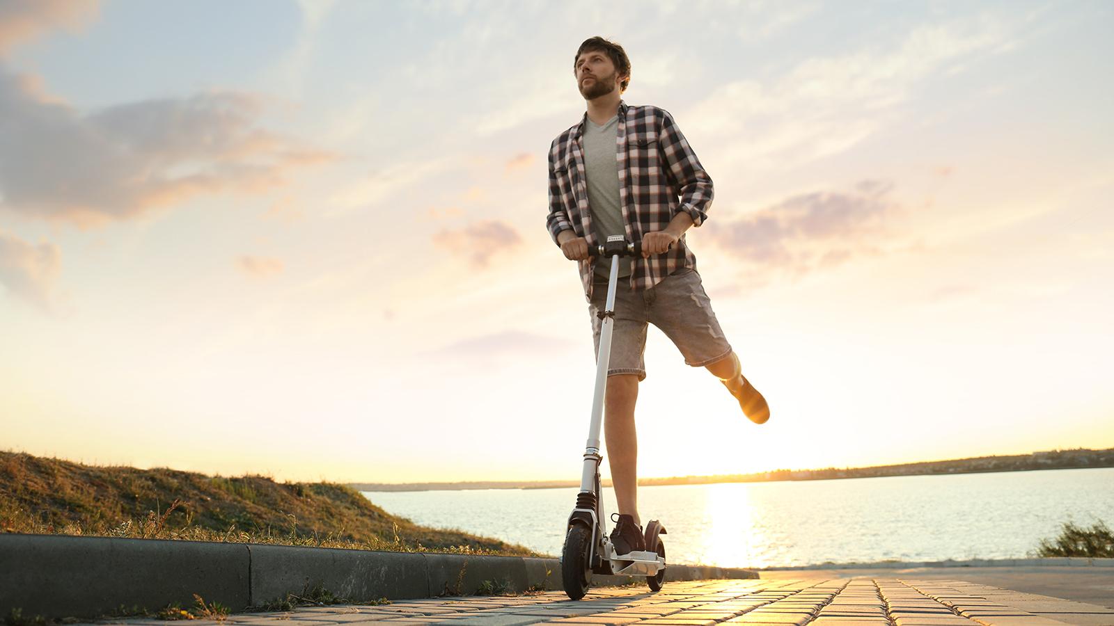 Junger Mann abends mit E-Scooter unterwegs